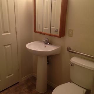 A minimalist bathroom with a pedestal sink and wall-mounted mirror.