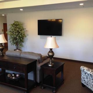 A cozy living room with a sofa, coffee table, lamps, and a wall-mounted TV.