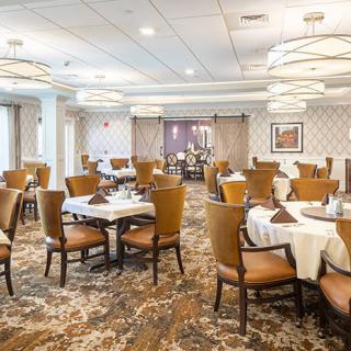 An elegant dining room with neatly arranged tables and chairs, featuring stylish lighting and decor.