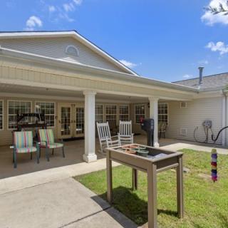 A spacious backyard patio with outdoor seating and a grill under a clear blue sky.