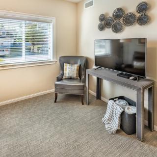 A modern living room with a television, armchair, and decorative wall art.