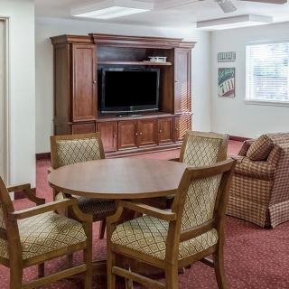 A cozy living room with a television, wooden furniture, and a carpeted floor.