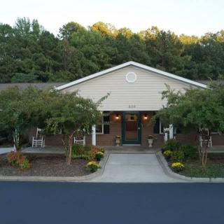 A building with a landscaped entrance surrounded by trees.