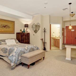 A cozy and well-decorated bedroom featuring a bed, dresser, wall art, and warm lighting.