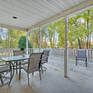 A covered outdoor patio with furniture overlooking a wooded area.