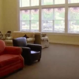 A spacious living room with large windows and various seating options.