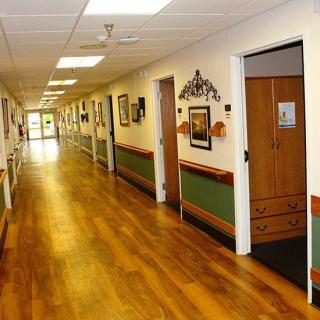 A well-lit hallway with wooden floors and artwork adorning the walls.