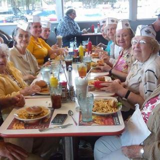 A group of seniors enjoying a meal together at a retro-style diner.