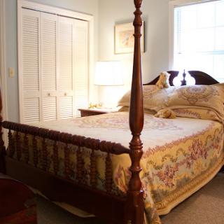 A cozy bedroom featuring a beautifully made four-poster bed, warm lighting, and elegant decor.