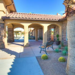 A beautiful house entrance with a porch and desert landscaping under a clear blue sky.