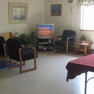A cozy living room with a television, chairs, and decorative elements.