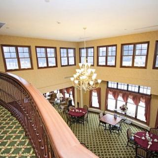 A spacious dining area with a chandelier, viewed from an upper-level balcony.