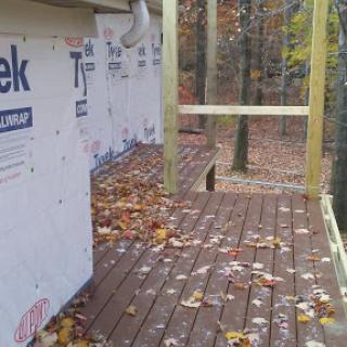 A partially finished outdoor deck surrounded by autumn leaves.