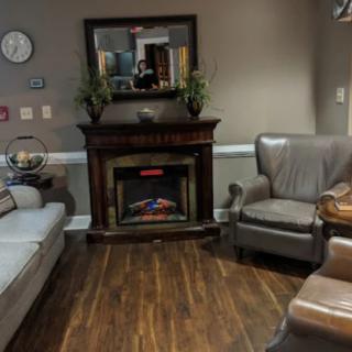 A cozy living room with a fireplace, sofa, and armchairs.