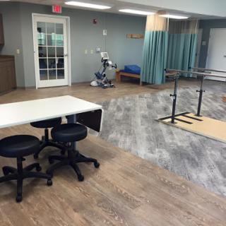 A spacious therapy room equipped with tables, chairs, and exercise equipment for rehabilitation.