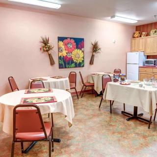 A cozy dining area with round tables, chairs, and floral decorations on pink walls.