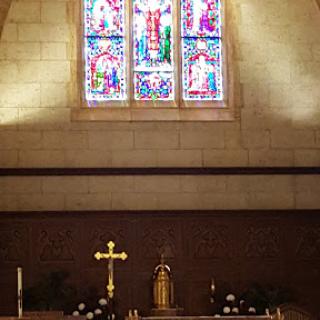 A serene view of the altar in a church, illuminated by colorful stained glass windows.