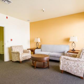 A cozy living room with a sofa, armchairs, and a coffee table set against an orange accent wall.