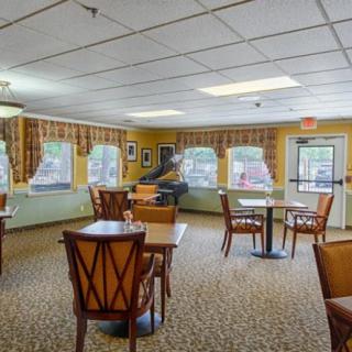 A cozy dining area with wooden tables and chairs, large windows, and tasteful decor.