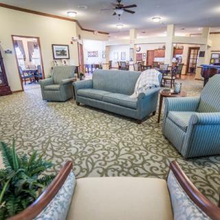 A spacious living room featuring comfortable seating with sofas and armchairs on a patterned carpet.