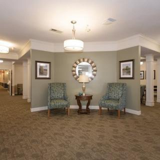 A well-decorated lobby area with two chairs, a table, and a mirror under soft lighting.