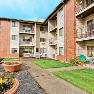 A well-maintained residential apartment complex with landscaped lawns and balconies.