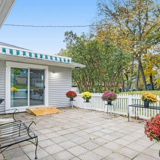 A cozy outdoor patio with colorful flowers and a striped awning, perfect for relaxation.