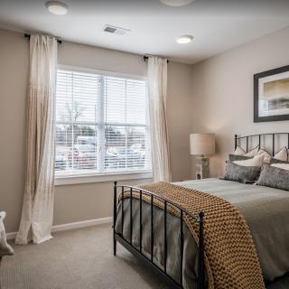 Cozy bedroom interior with a metal frame bed and large window.
