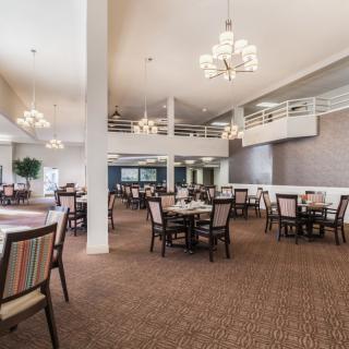 A spacious dining area with elegant chandeliers and neatly arranged tables and chairs.