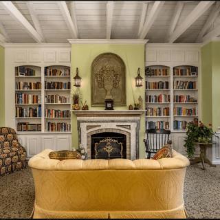 A cozy living room with a central fireplace, surrounded by built-in bookshelves and a plush sofa.