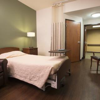 A hospital room with a bed, lamp, and chairs, creating a comfortable healthcare setting.