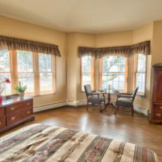 A cozy bedroom interior with large windows and elegant furnishings.