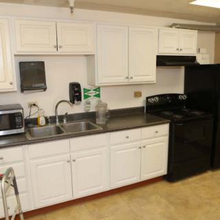 A modern kitchen with white cabinets, equipped with appliances including a microwave, oven, and refrigerator.