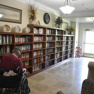 A cozy library space featuring well-stocked shelves and a wheelchair user enjoying a moment of reading.