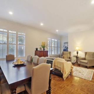 A spacious and well-lit living and dining area with elegant furniture and large windows.