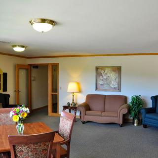 A cozy living room with a sofa, chairs, and a dining table, featuring soft lighting and tasteful decor.
