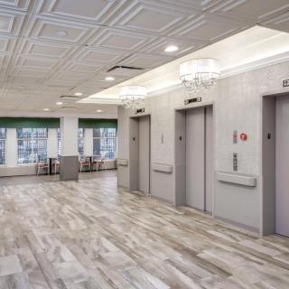 A modern elevator lobby with bright lighting and wooden flooring.