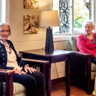 Two elderly women are seated in a cozy living room, enjoying a relaxed moment together.