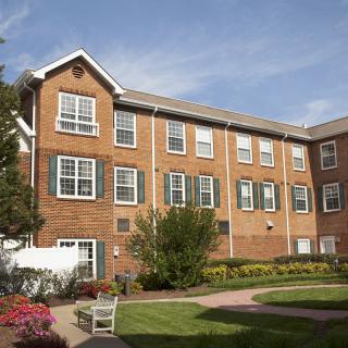 A brick residential building with a landscaped garden under a clear blue sky.