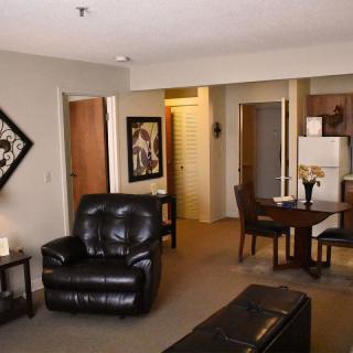 A cozy living space with leather furniture and an open dining area connected to the kitchen.