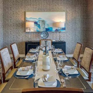 A beautifully set dining table in an elegant dining room with sophisticated decor and wall art.