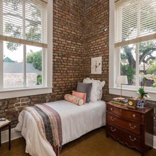 Cozy bedroom with exposed brick walls and large windows letting in natural light.