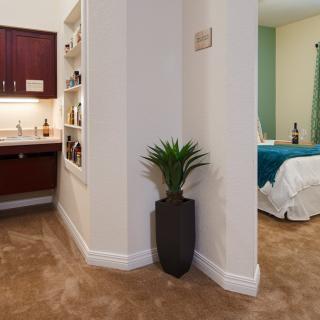 A cozy bedroom corner with a plant and view into a bathroom area.
