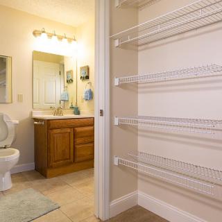 A clean and well-lit bathroom interior with a wooden vanity, mirror, toilet, and built-in shelves.