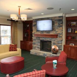 A cozy living room featuring a stone fireplace, wall-mounted television, and comfortable seating.