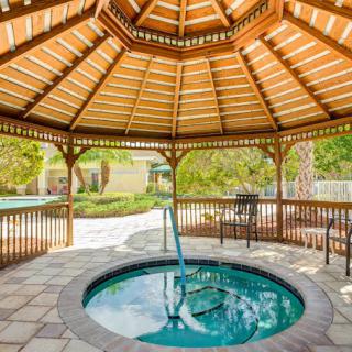 A wooden gazebo with a hot tub, set in a landscaped garden area.