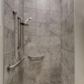 A tiled shower with safety grab bars installed.