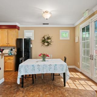 A cozy dining area with a table set for two, adjacent to a kitchen with wood cabinets and bright natural light coming through the sliding doors.