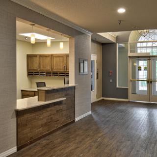 A modern lobby featuring a reception desk and wooden cabinetry, illuminated by soft lighting.
