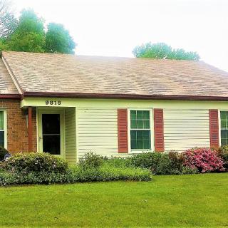 A single-story suburban house with a well-maintained front lawn and garden.